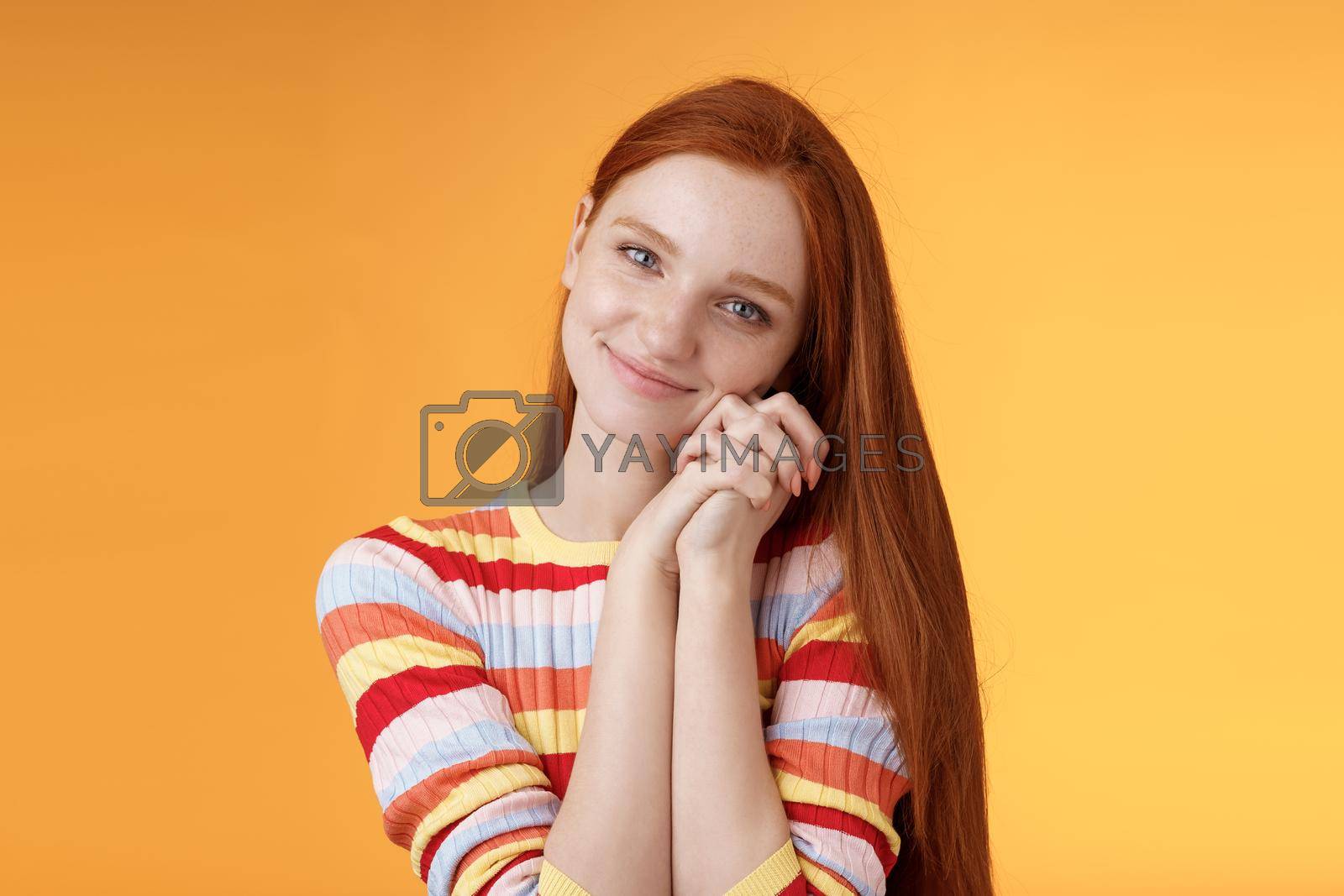 Royalty free image of Dreamy sensual romantic young passionate redhead girlfriend melt heart feel sympathy joy receive sweet tender present lean palms smiling grateful gladly accept nice lovely gift, orange background by Benzoix