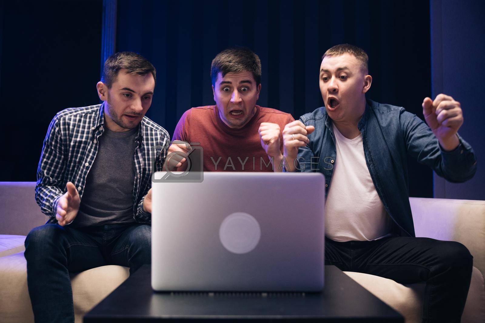 Royalty free image of Male friends watching online football game match at laptop. Men fans buddies supporters cheering celebrating victory goal score support winning team. Men watching football in streaming on laptop by uflypro