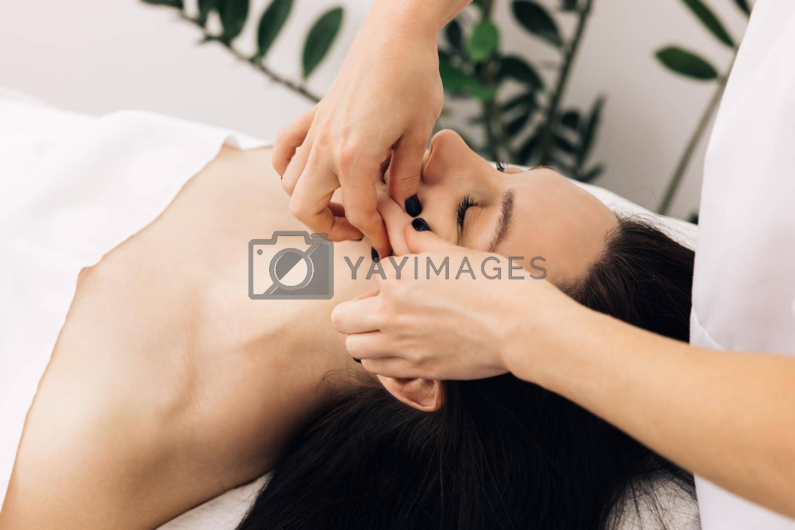 Face Massage in beauty spa salon. Female enjoying relaxing face massage in cosmetology spa centre. Body care, skin care, wellness, beauty treatment. Spa woman facial Massage.