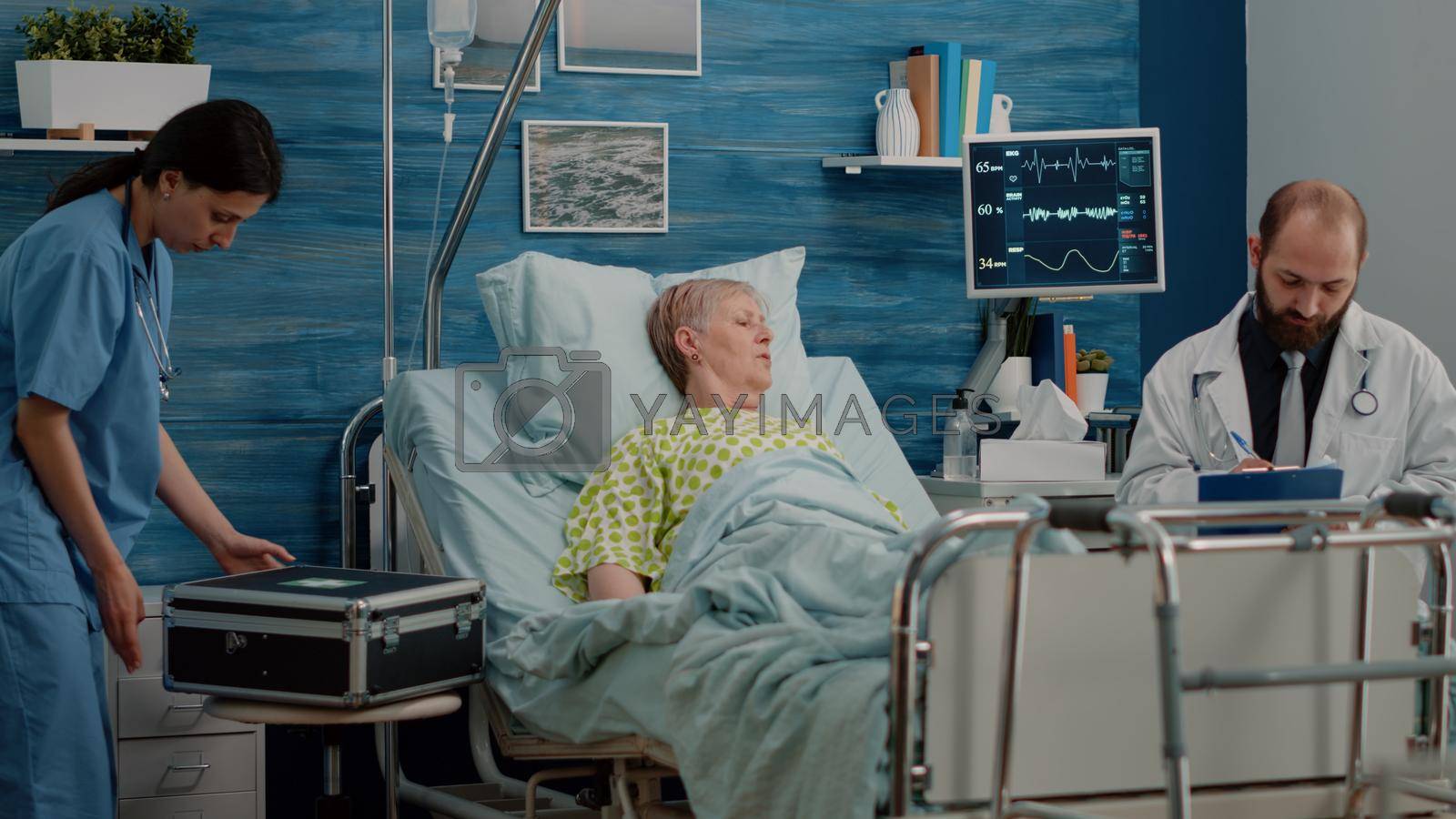 Doctor and nurse doing healthcare checkup with retired woman in bed. Medical team consulting elder patient with sickness, using equipment and heart rate monitor. Person at examination