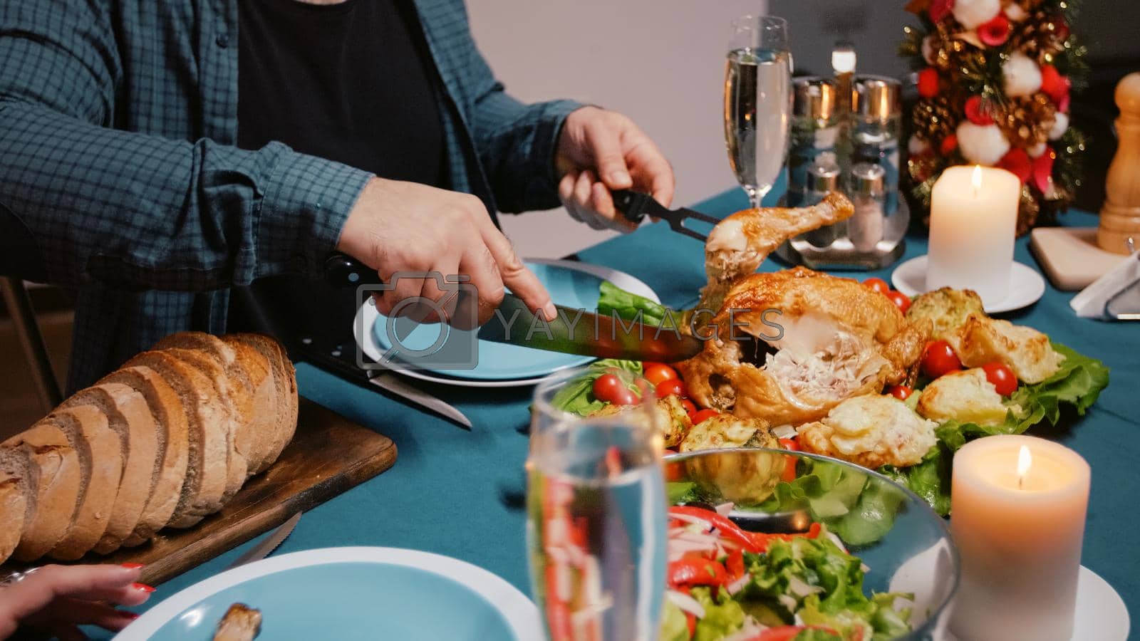 Close up of man cutting meal at christmas dinner celebration. Adult preparing chicken for woman, enjoying festive food and drinking champagne. Holiday festivity with food and alcohol