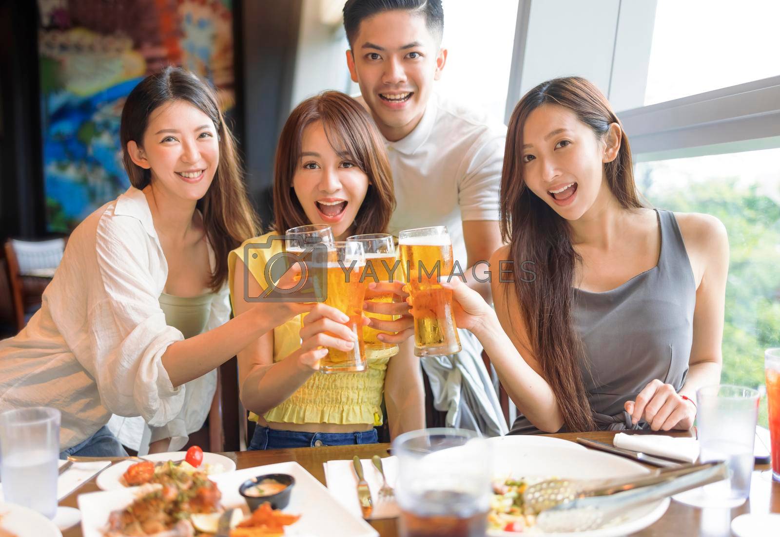 Happy Young friends enjoying food and beer in restaurant
