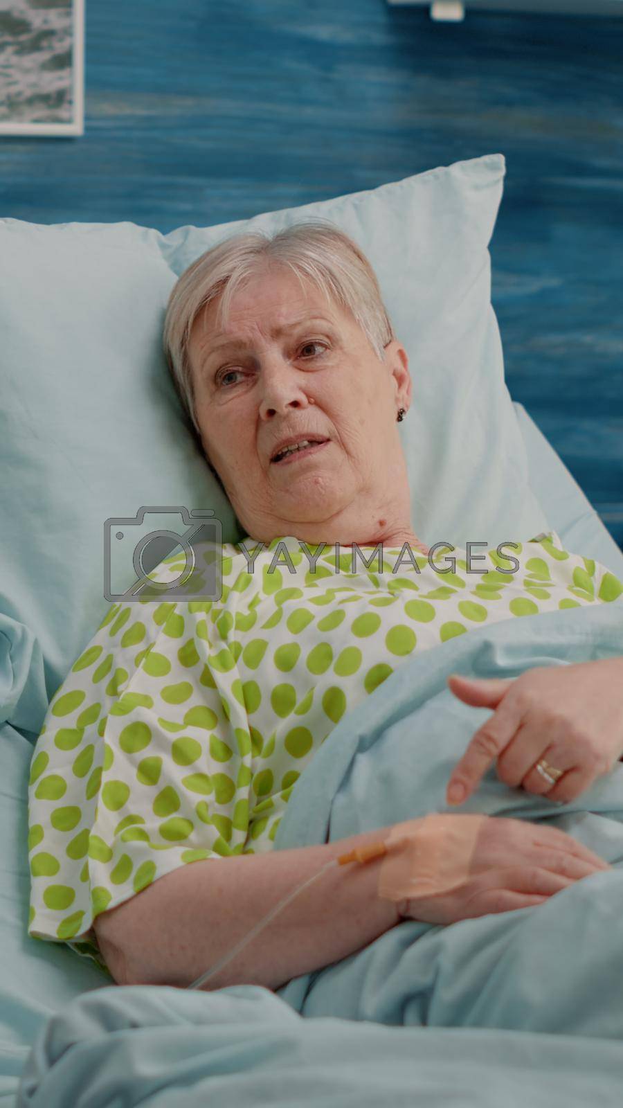 Doctor doing healthcare consultation with retired patient in bed at nursing home. Aged woman with illness talking to specialist about healing treatment and recovery with medication