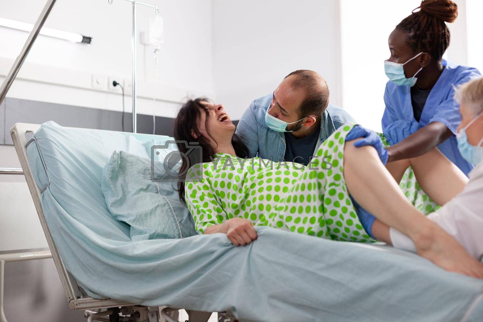 Royalty free image of Young woman giving birth and pushing in hospital ward bed by DCStudio