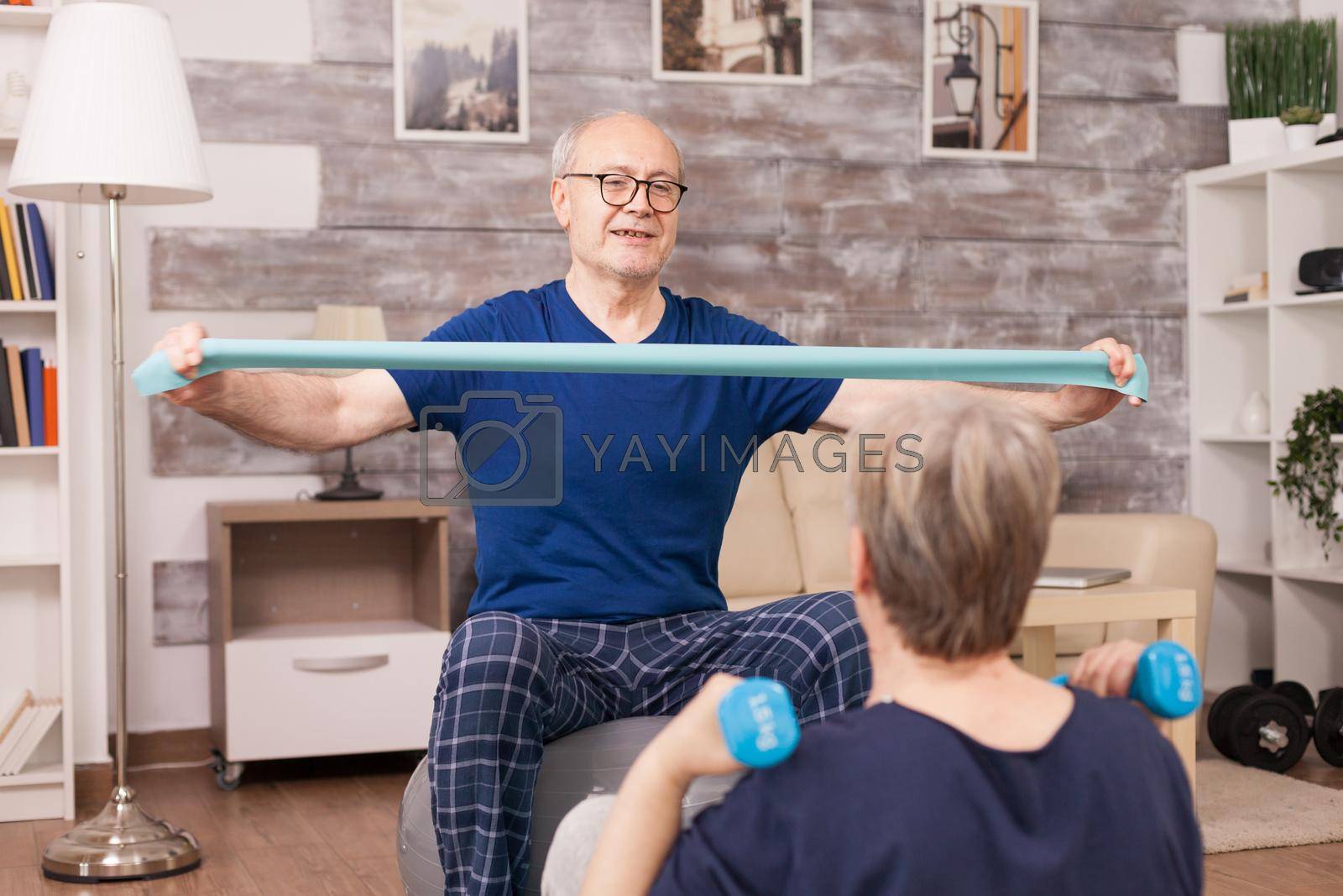 Elderly people toning their arms sitting on yoga mat. Old person healthy lifestyle exercise at home, workout and training, sport activity at home.
