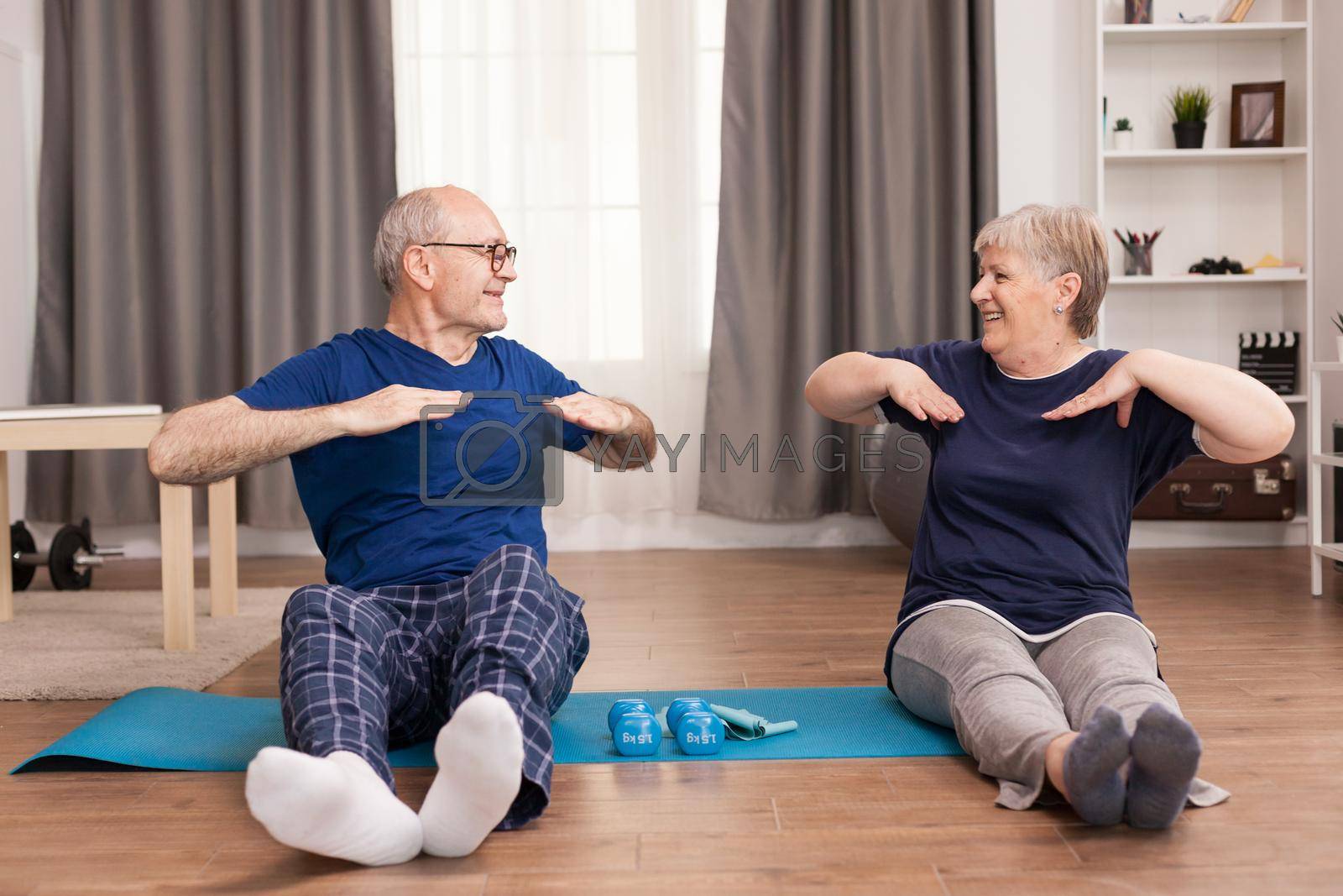 Aged people stretching on yoga mat and smiling at each other. Old person healthy lifestyle exercise at home, workout and training, sport activity at home.