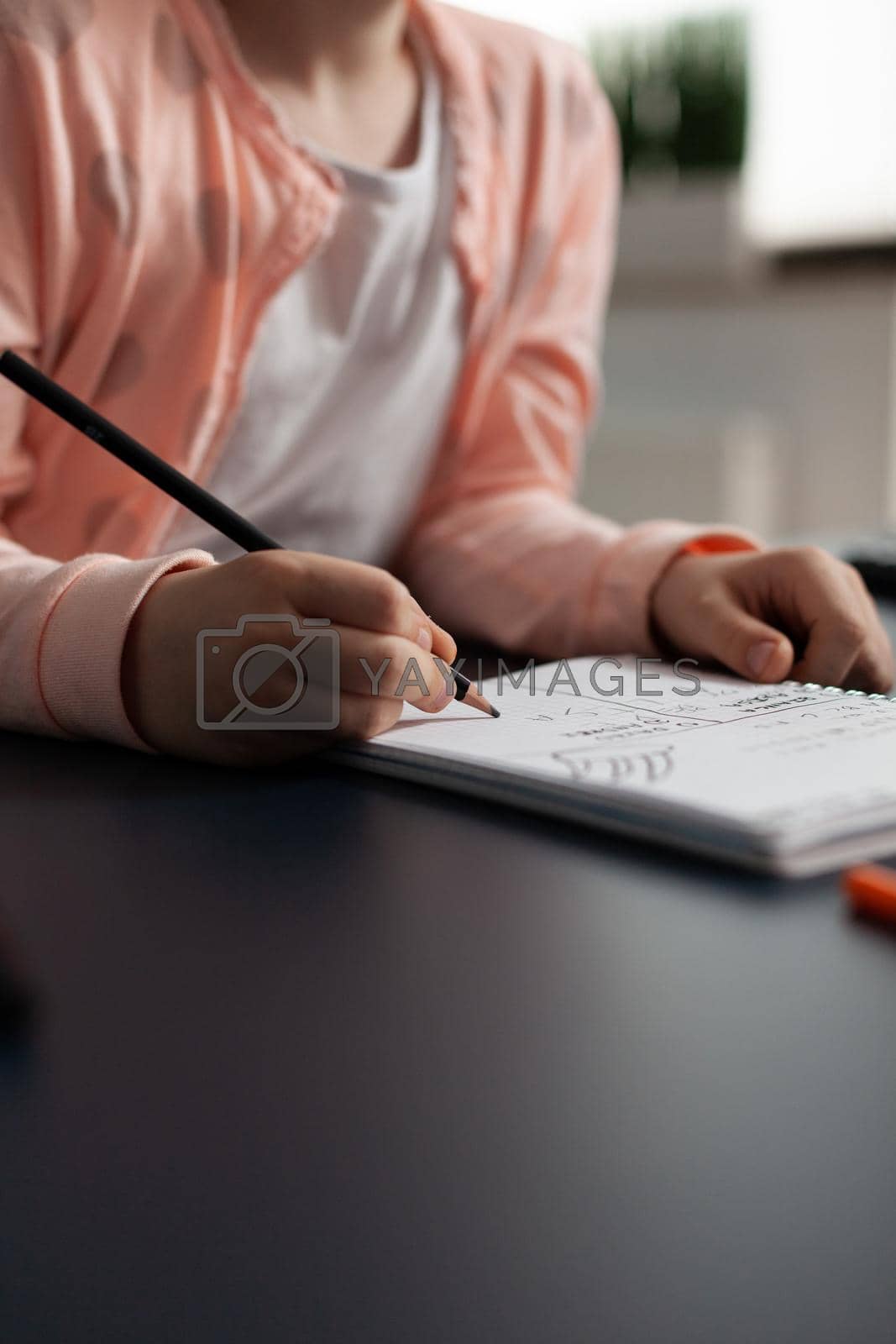 Royalty free image of Closeup of little schoolchild writing mathematics homework on notebook by DCStudio