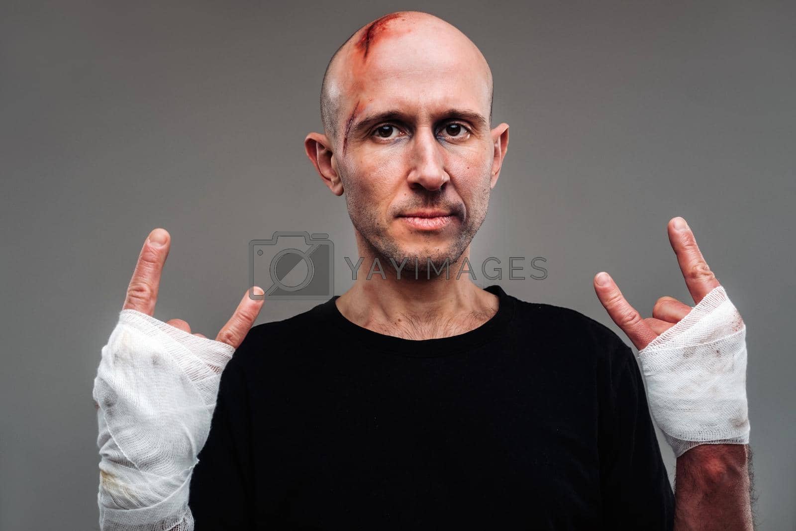 Royalty free image of On a gray background stands a battered man in a black T-shirt With his hands wrapped up by Lobachad