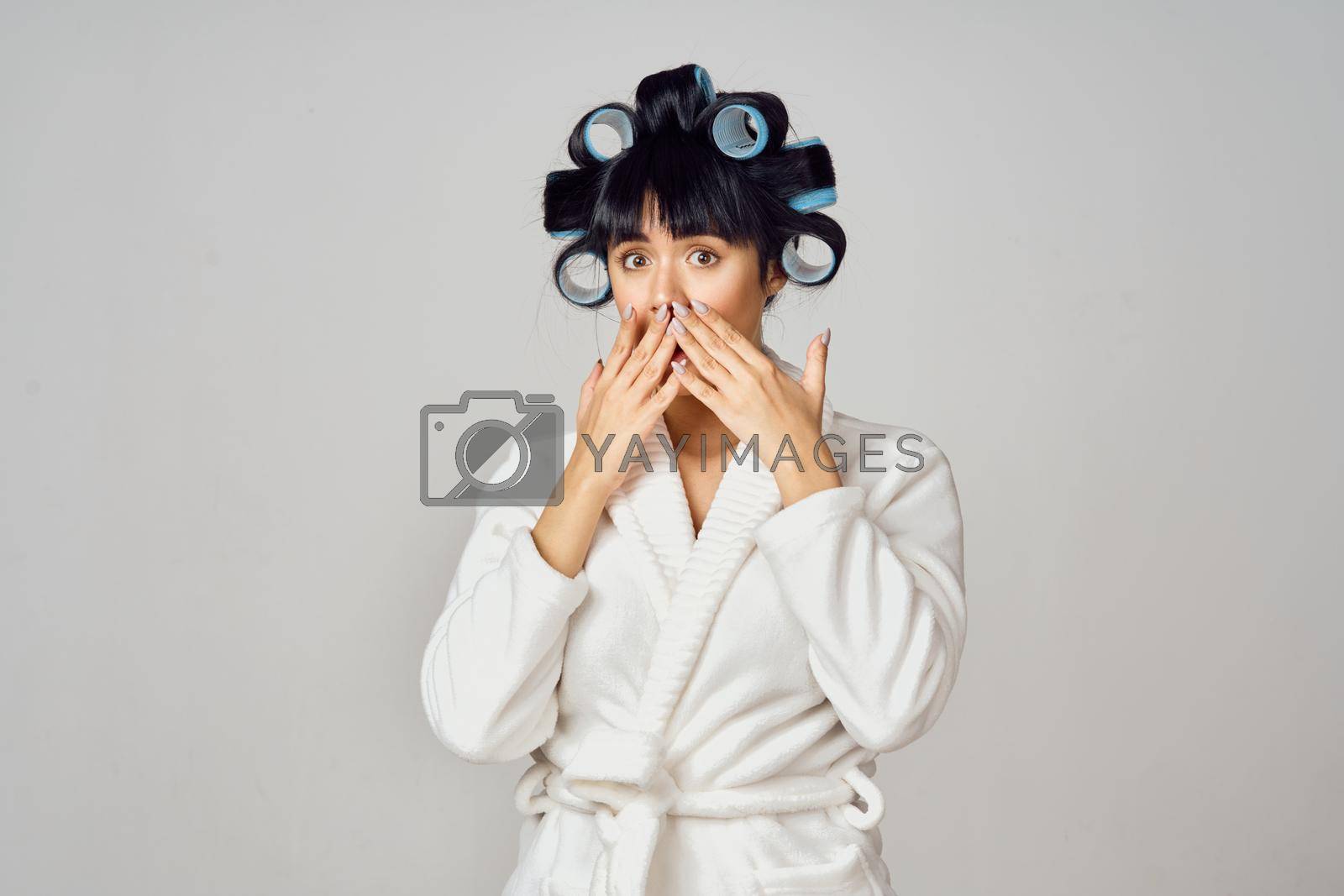 Royalty free image of Woman in a white robe with curlers on her head doing homework in the kitchen by Vichizh