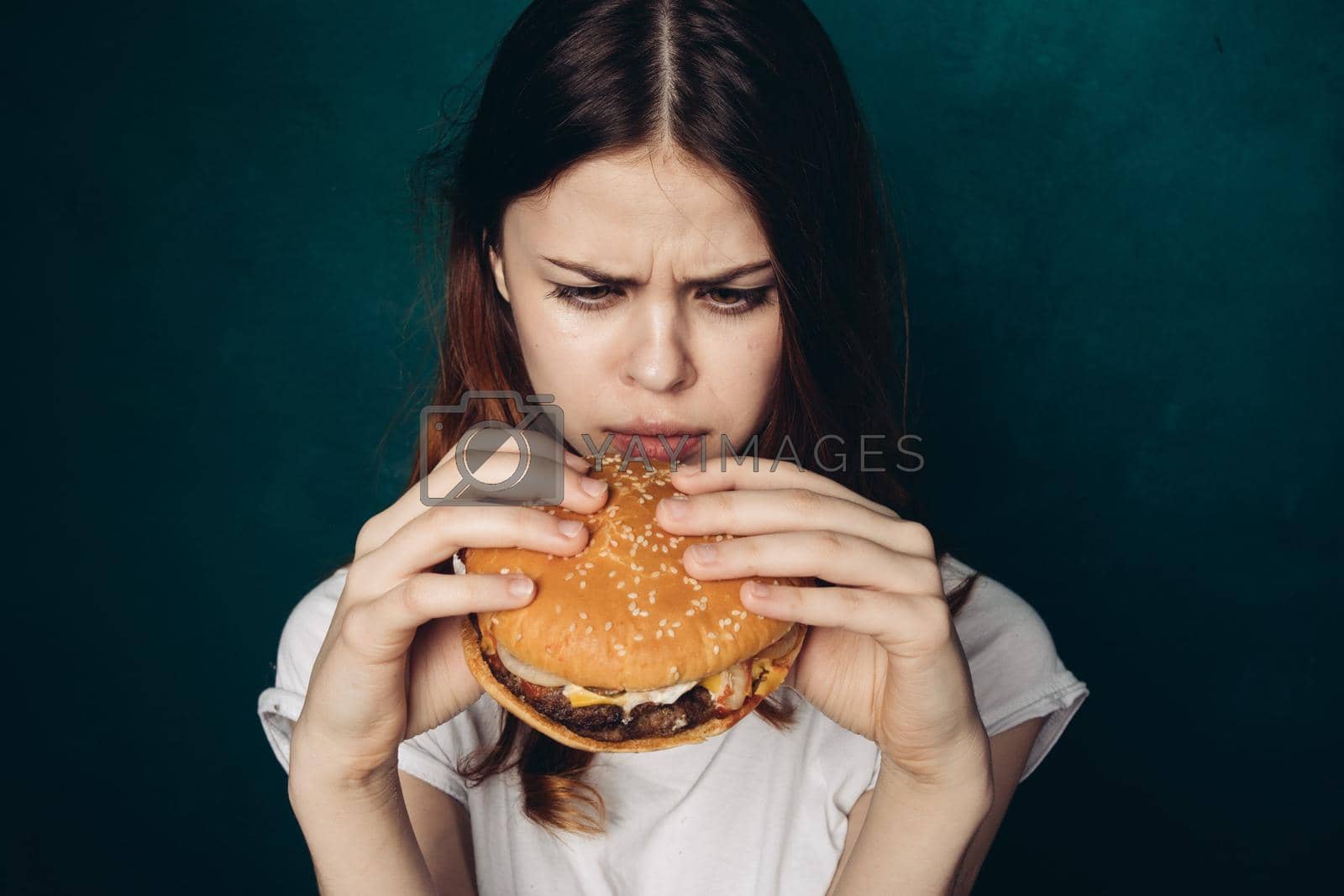 Royalty free image of cheerful woman with hamburger near face snacking fast food by Vichizh