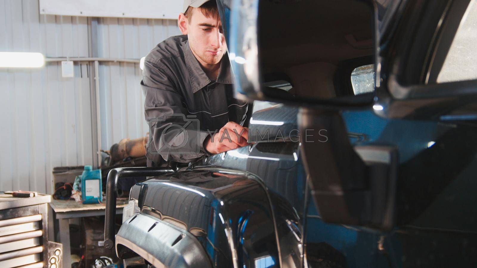 Royalty free image of Mechanic looking to hood of the car - automobile service repairing by Studia72