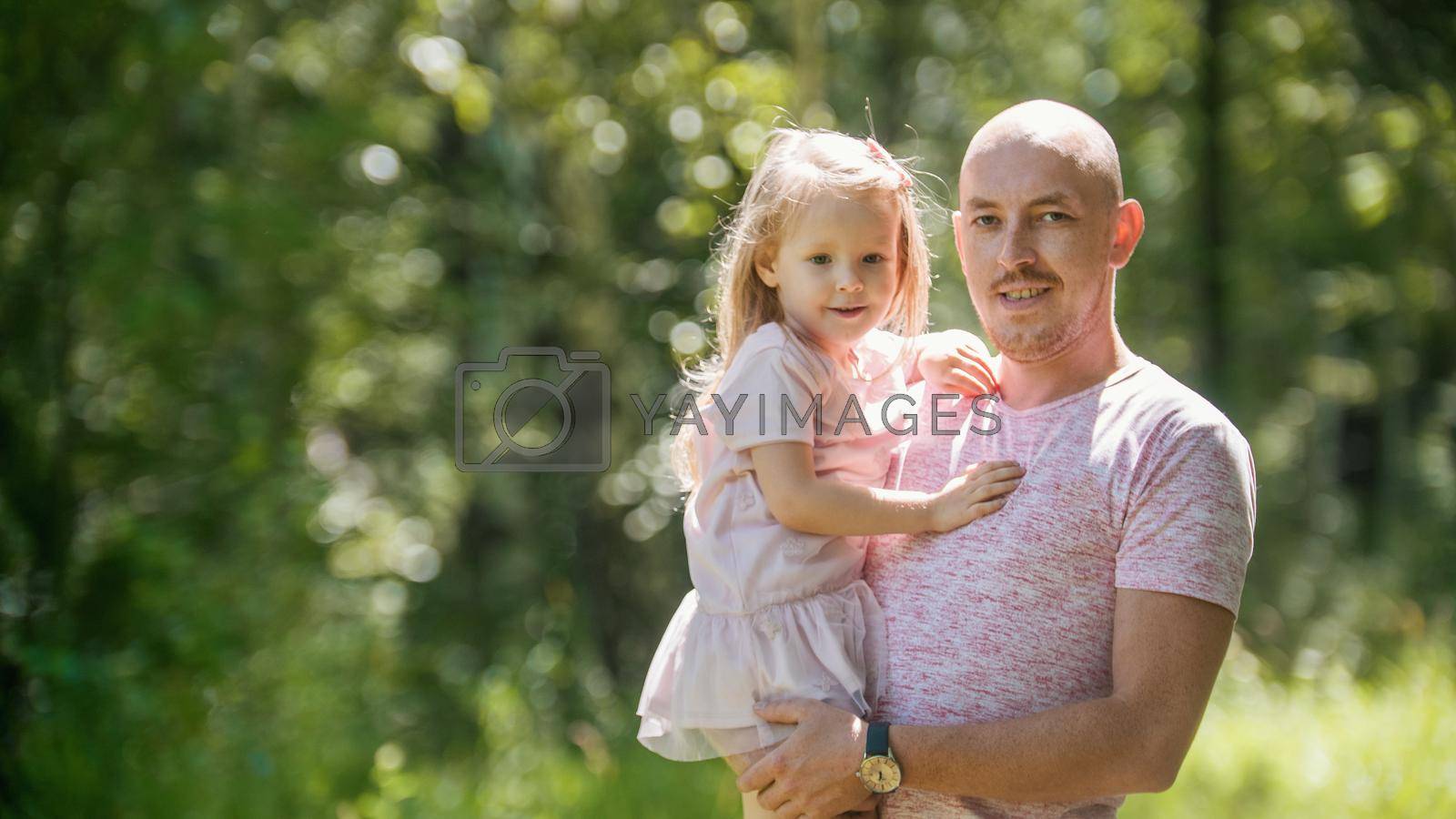 Happy family - father with daughter in summer park, telephoto view
