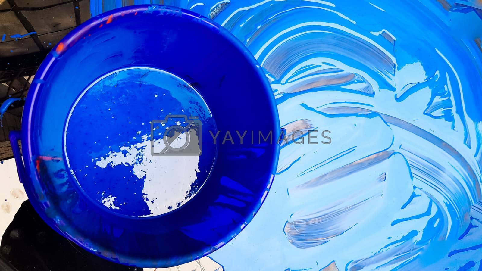 Royalty free image of Abstract background of spilled blue paint with buckets on a black background. Blue paint is pouring on a black background. Use it for an artist or creative concept. Paints spilled blue background by Roshchyn