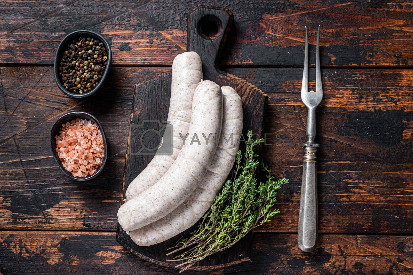 Royalty free image of Munich traditional white sausages on a wooden board with thyme. Dark wooden background. Top view by Composter