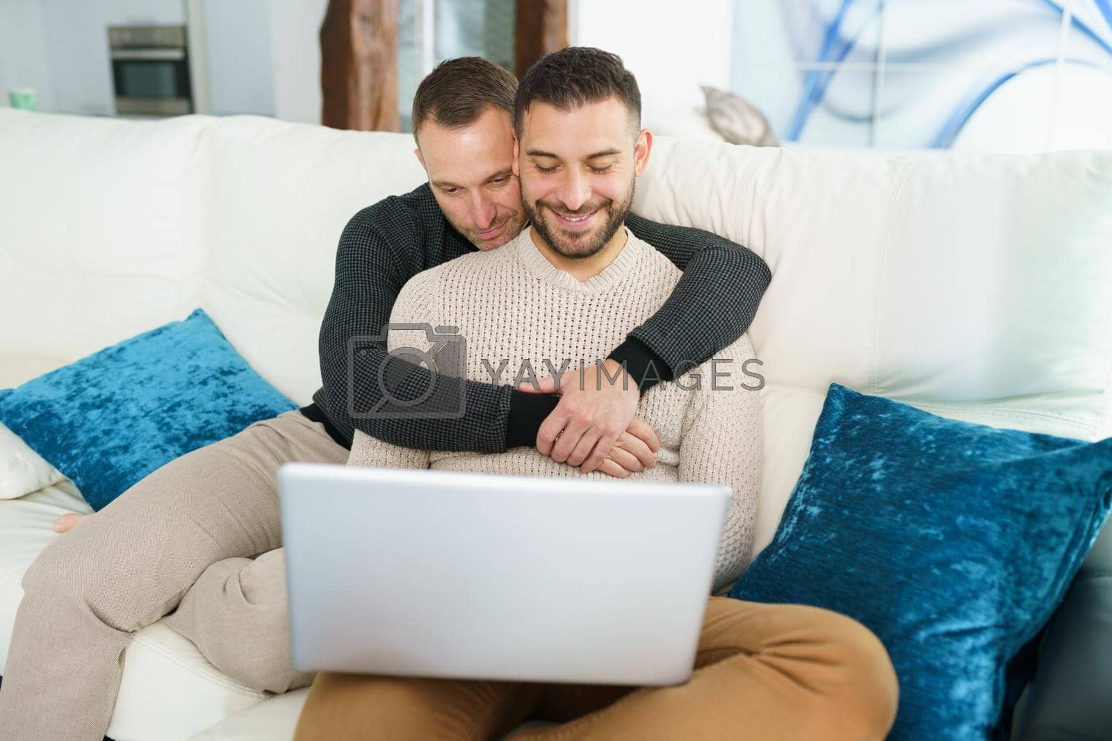 Gay couple consulting their travel plans together with a laptop. Homosexual Lifestyle concept.