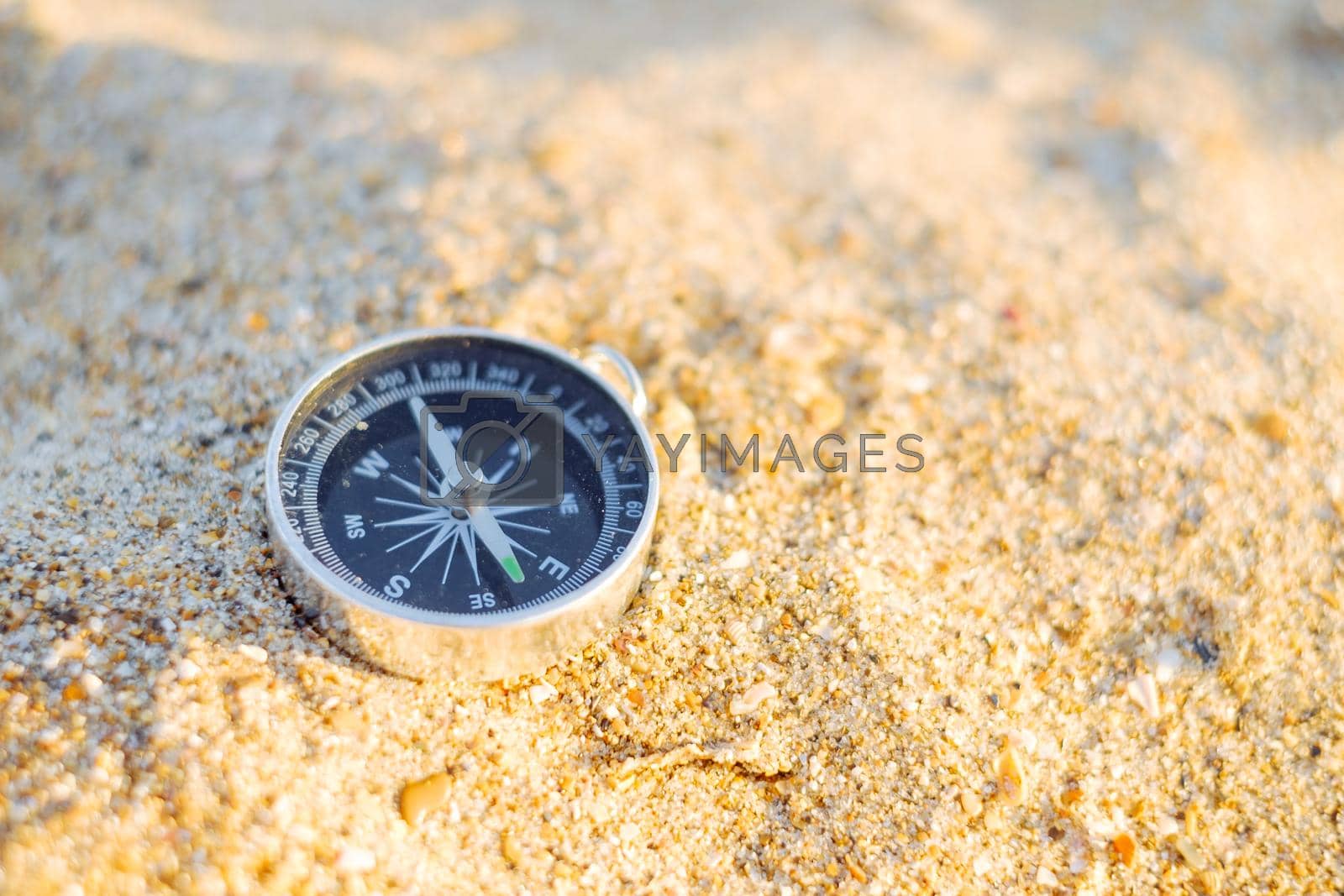 Travel magnetic compass on sand outdoor, nobody.