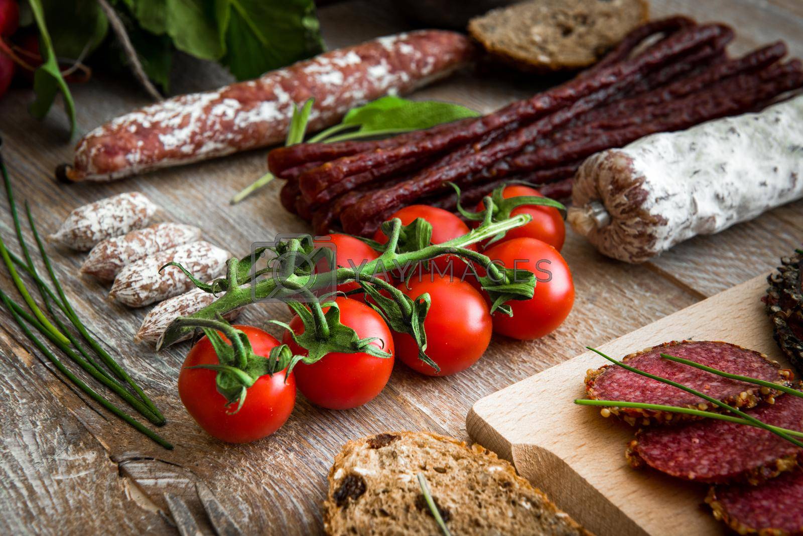 Royalty free image of bunch of cherry tomatoes with salami sausages by GekaSkr