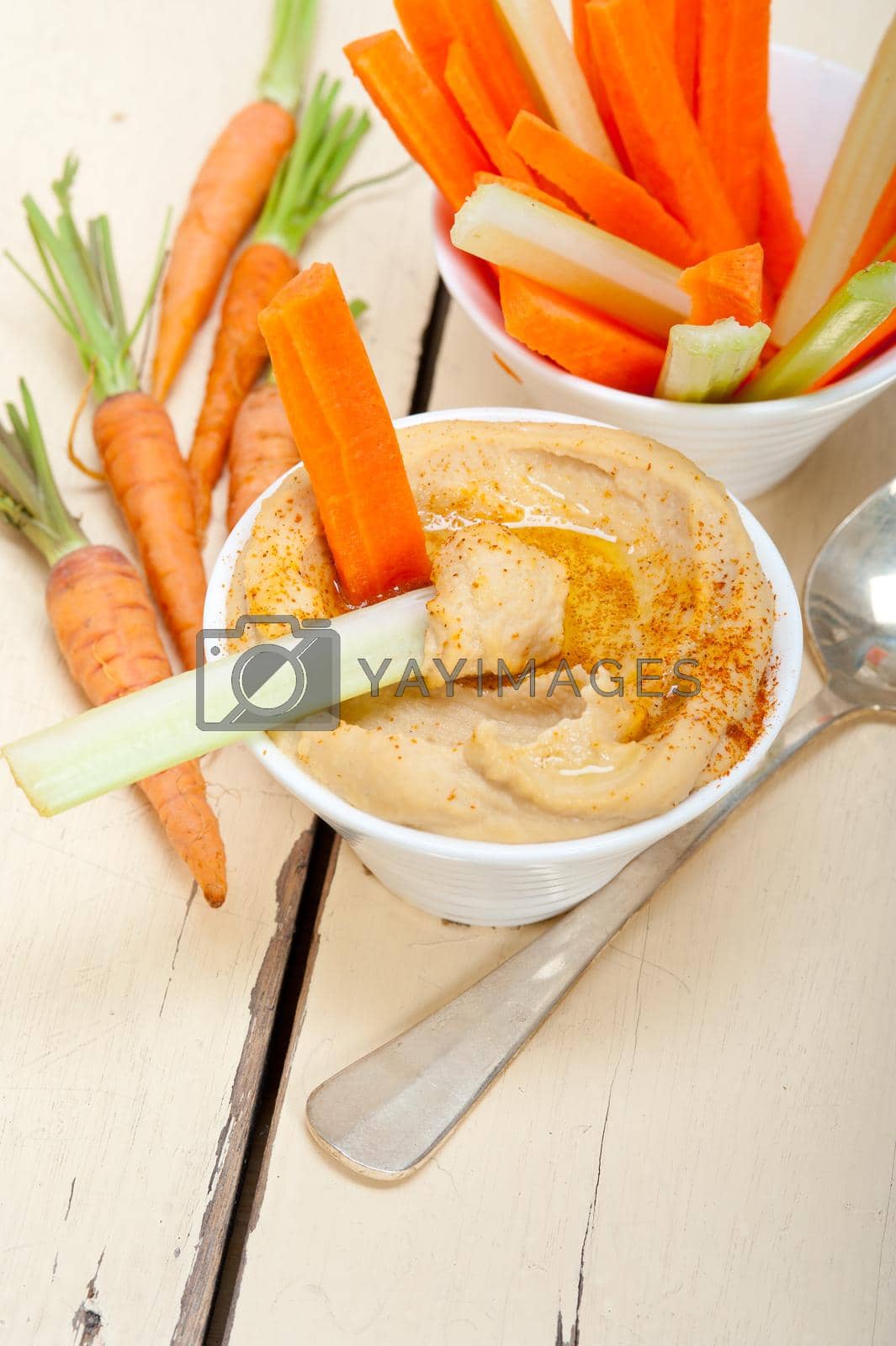 Royalty free image of fresh hummus dip with raw carrot and celery  by keko64