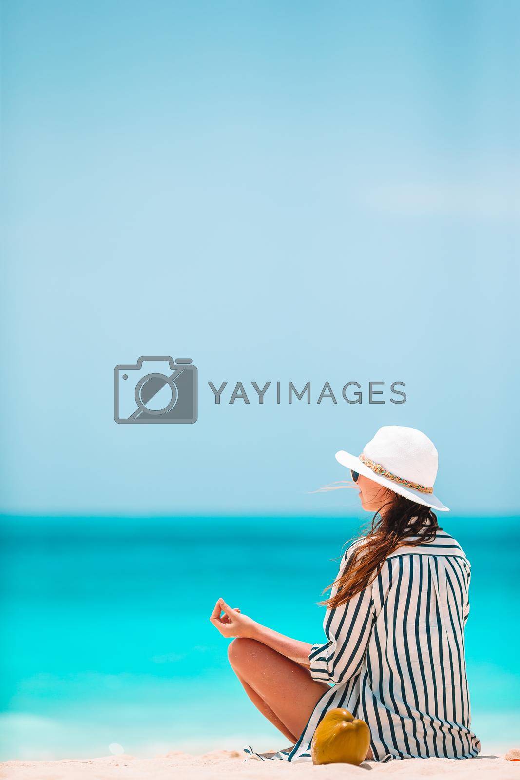 Young beautiful woman on yoga on white sand tropical beach.
