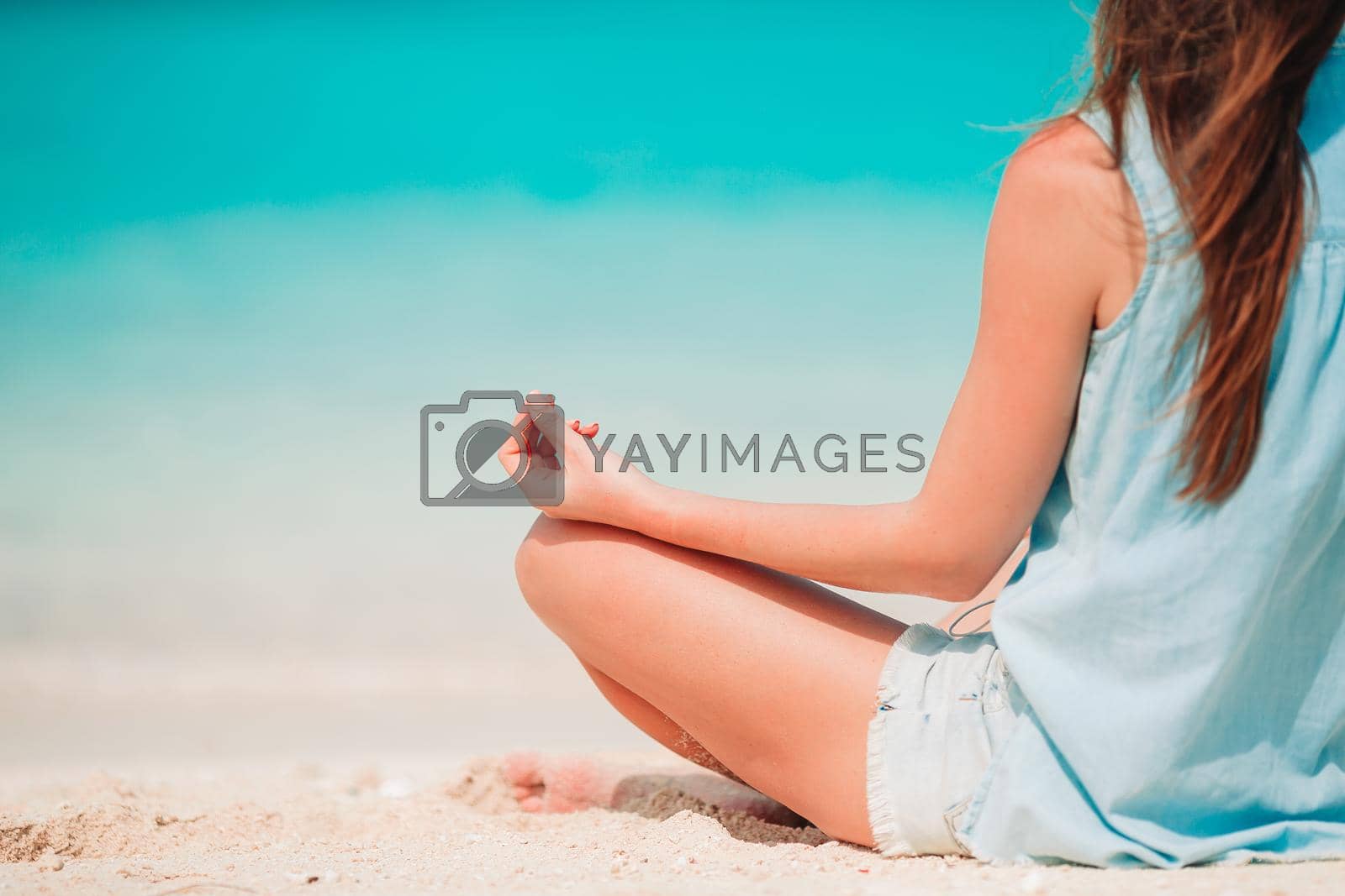Young beautiful woman on yoga on white sand tropical beach.