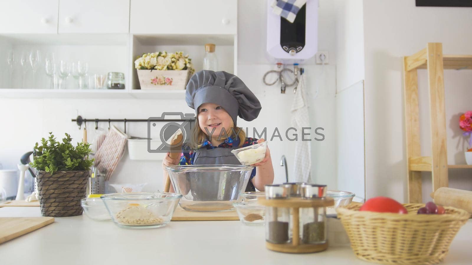Royalty free image of Little girl baker puts batter to the pastry dough for cooking biscuits by Studia72