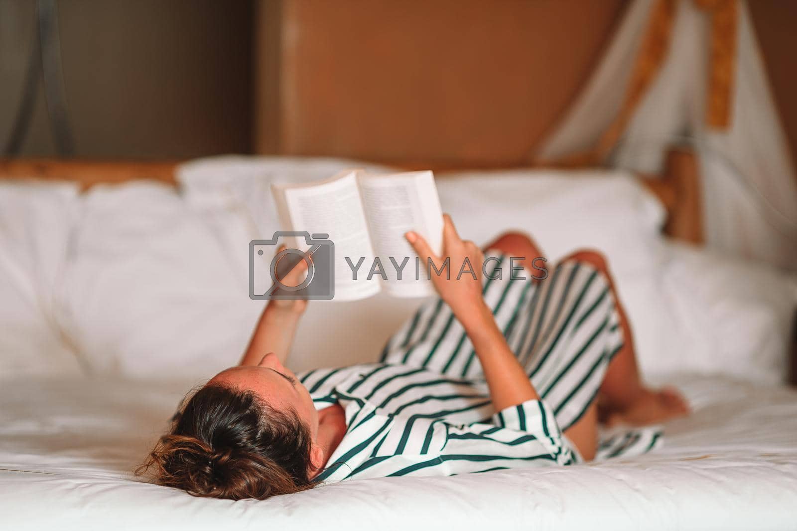 Royalty free image of Beautiful woman reading book in bed relaxing by travnikovstudio