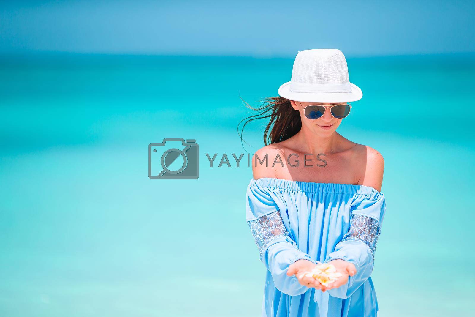 Young beautiful woman on white beach with tropical flower