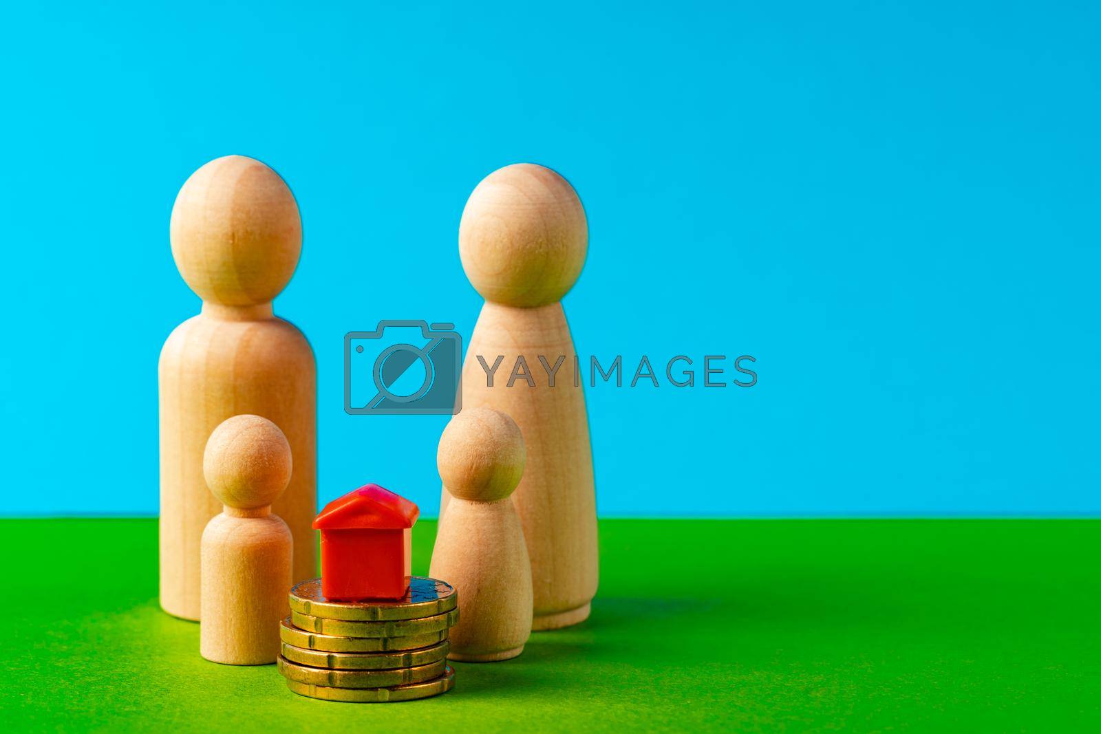 Royalty free image of Wooden family with toy house and stack of coins. Savings for house purchase concept by Fabrikasimf