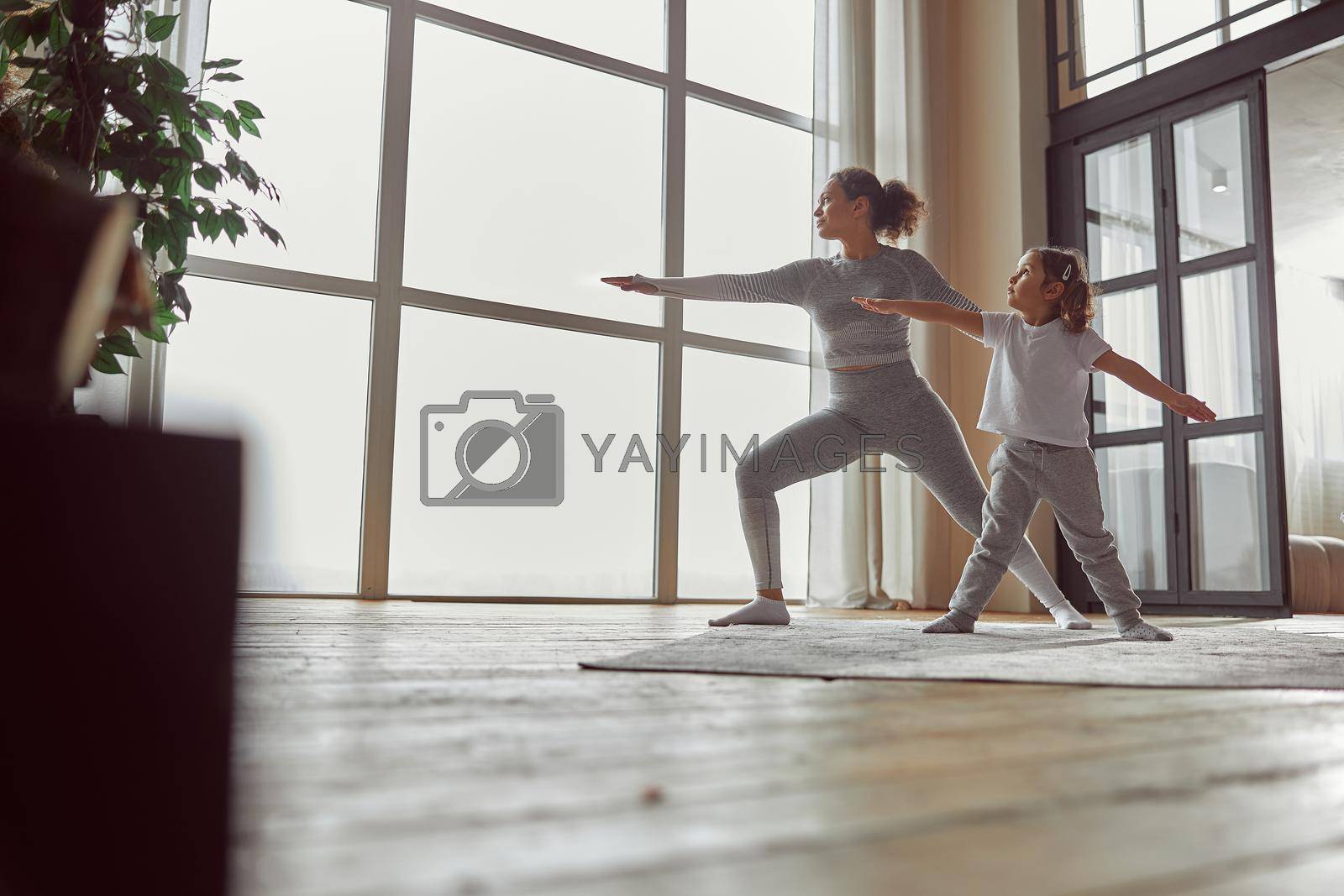 Low angle of calm woman standing in asana while her daughter is repeating after her