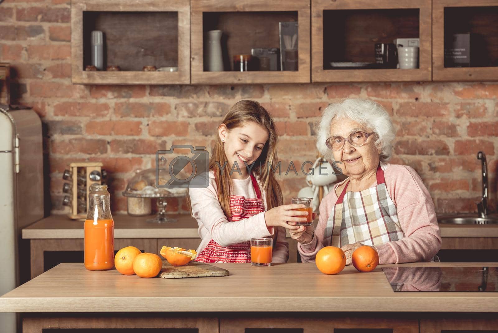 Royalty free image of Granny with granddaughter tasting orange juice at kitchen by tan4ikk1