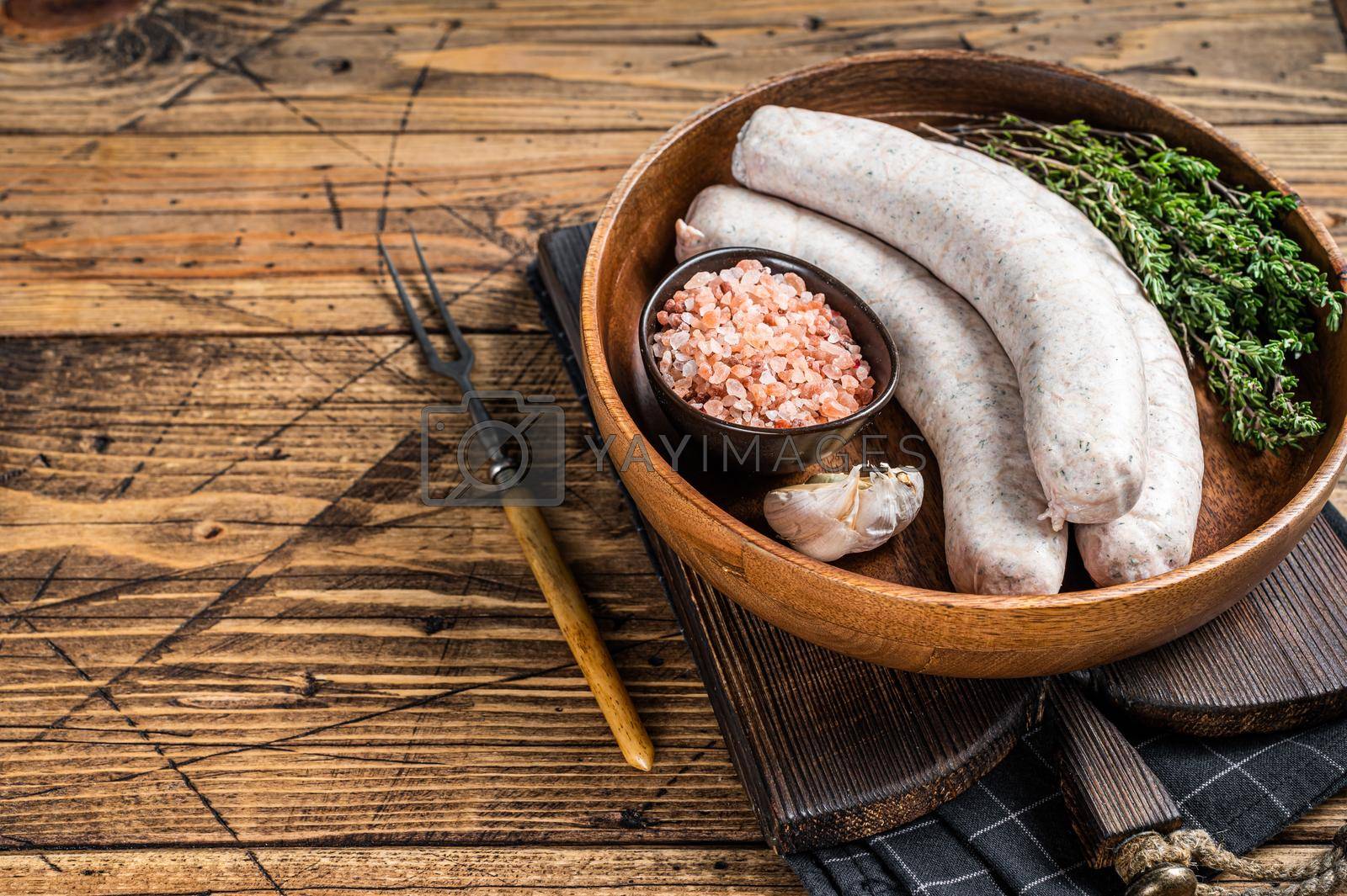 Royalty free image of Raw Munich traditional white sausages in a wooden plate with herbs. wooden background. Top view. Copy space by Composter