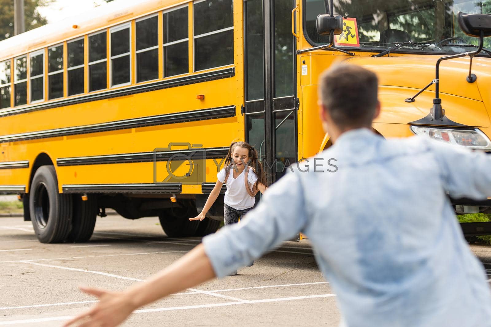 Father meeting little daughter coming out of school bus