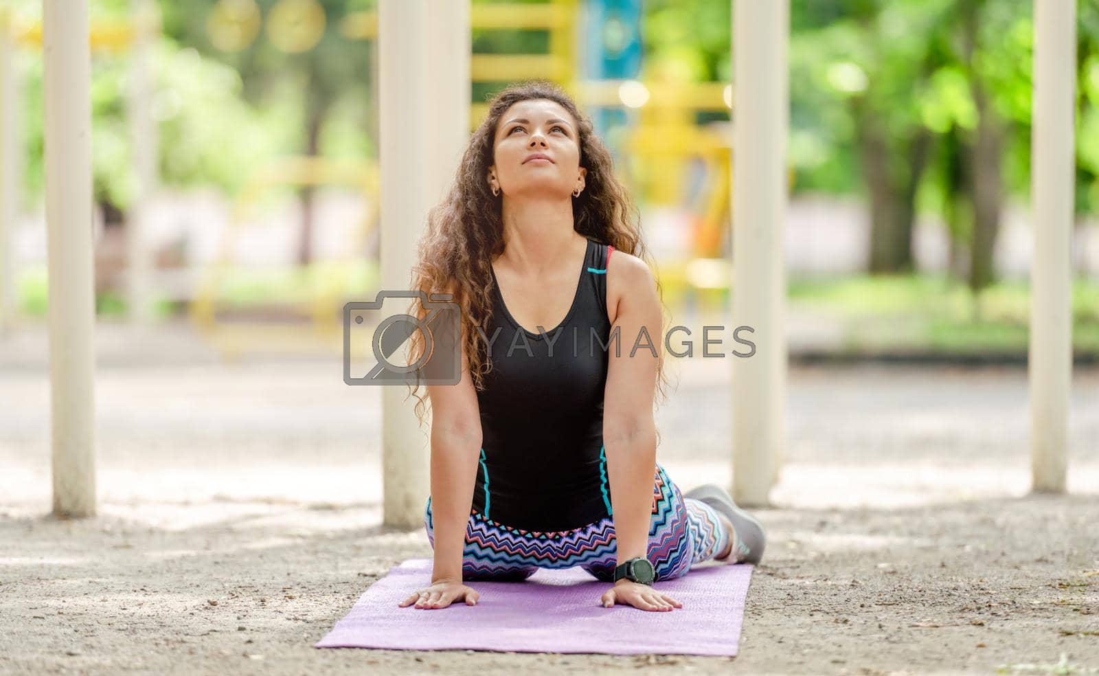 Pretty girl doing yoga upward facing dog pose during workout outdoors. Young woman stretching at stadium