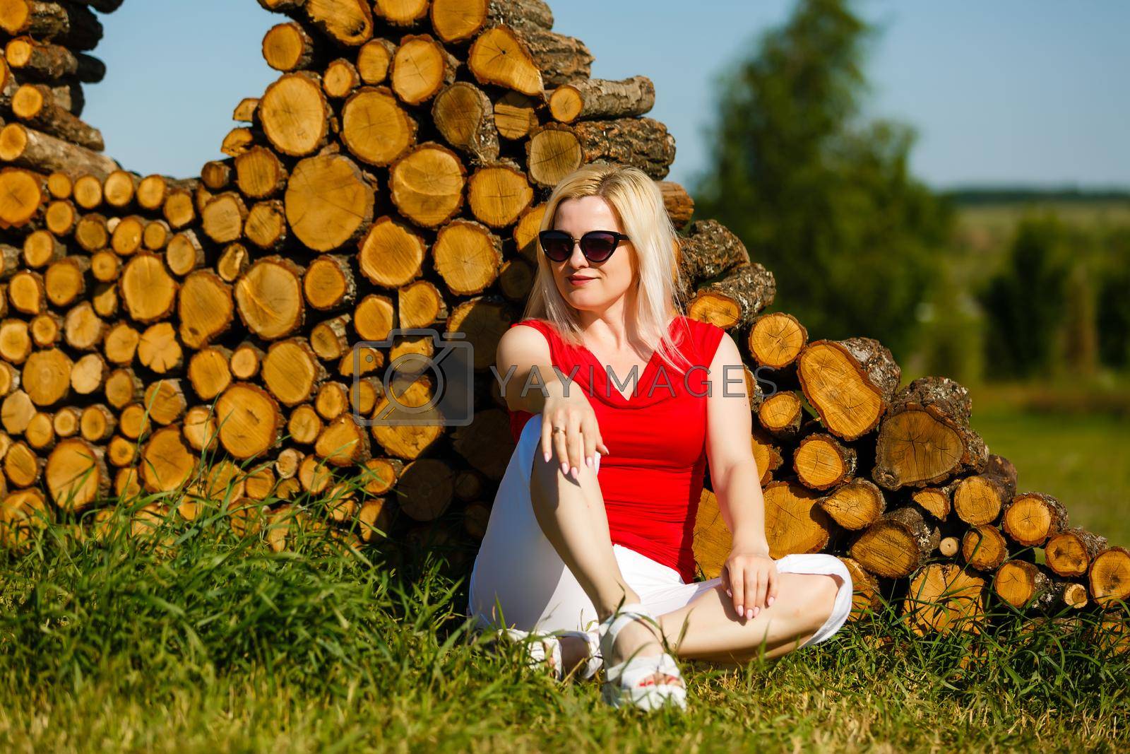 Royalty free image of woman sitting against tree in the park on the grass by Andelov13
