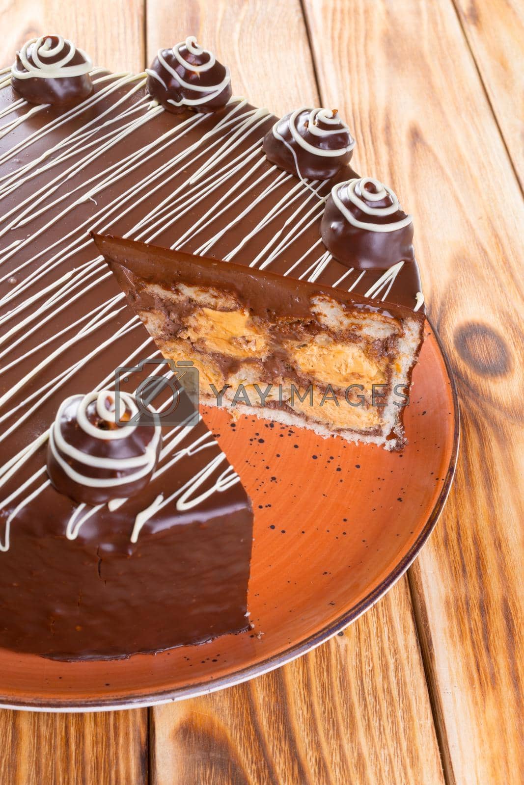 Royalty free image of Cut chocolate cake on plate on wooden table by Fabrikasimf