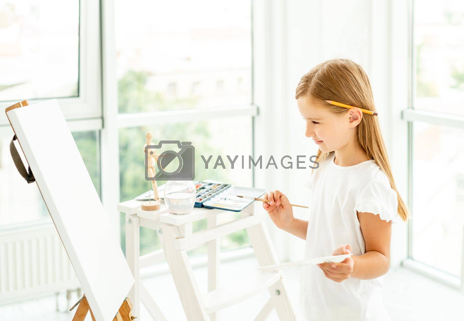 Royalty free image of Kid girl painting different pictures on easel by tan4ikk1