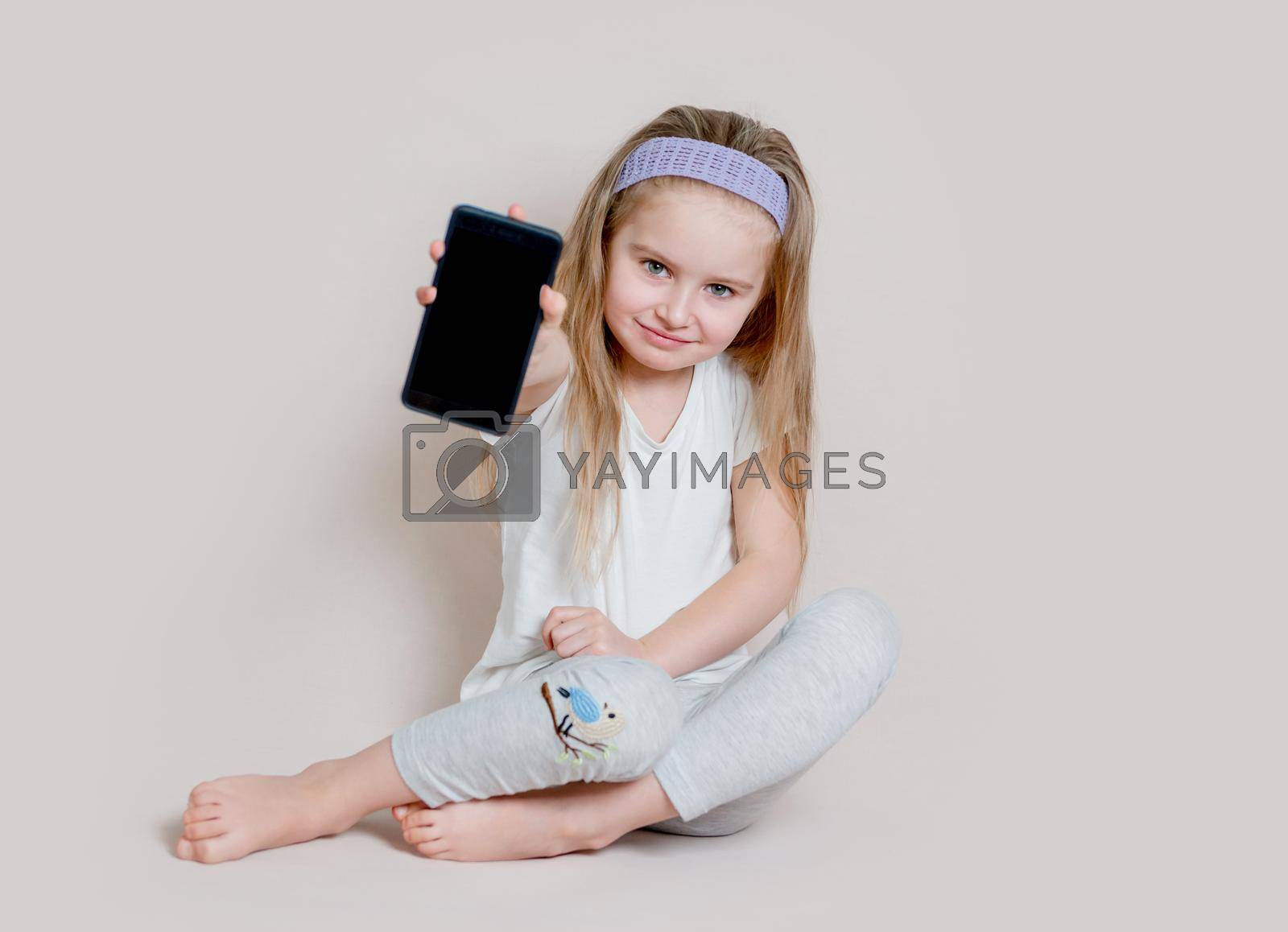 Royalty free image of Little girl showing blank screen of mobile phone by tan4ikk1