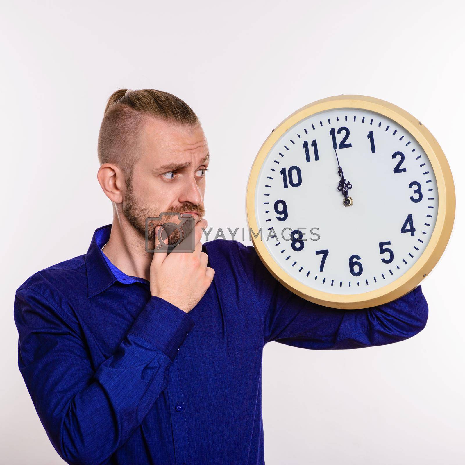Royalty free image of A stylish man thinks out the idea and holds a large wall clock by zartarn