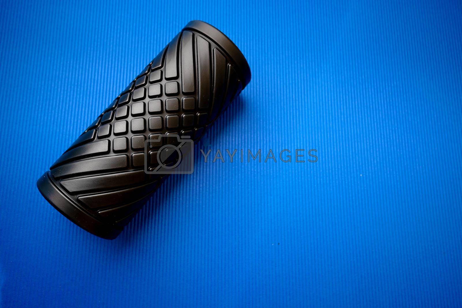 Sport fitness foam roller on blue mat, close up