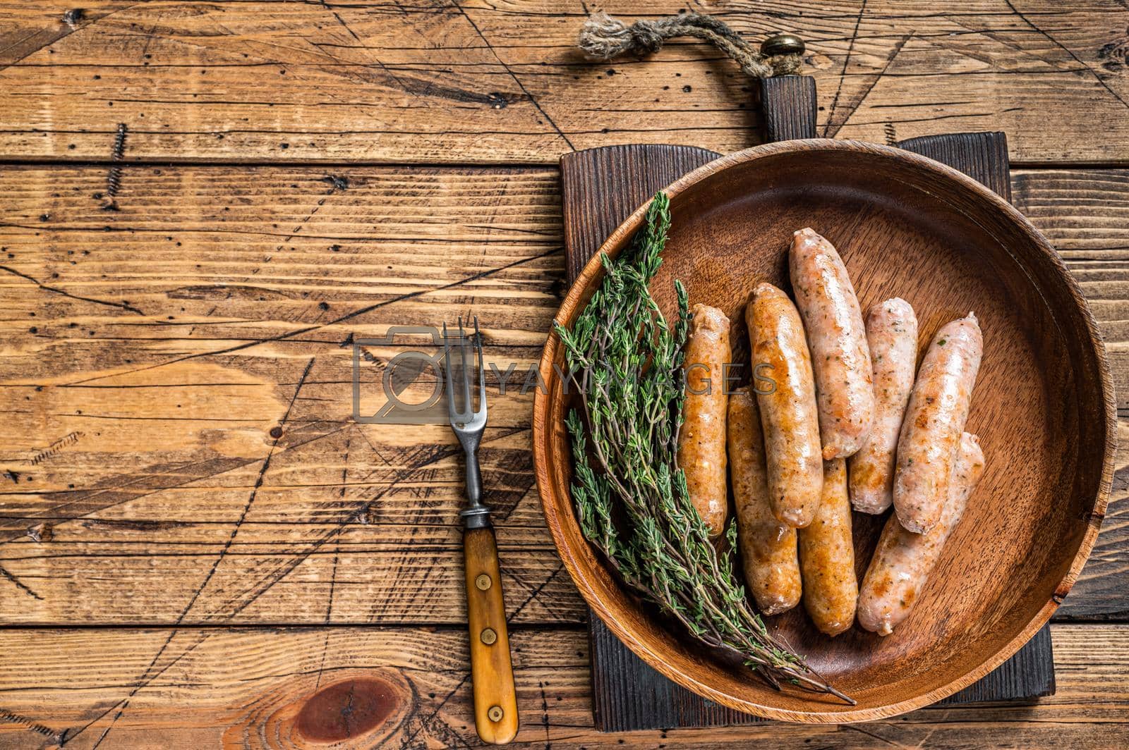 Royalty free image of Fried Chorizo and Bratwurst sausages in a wooden plate. wooden background. Top View. Copy space by Composter