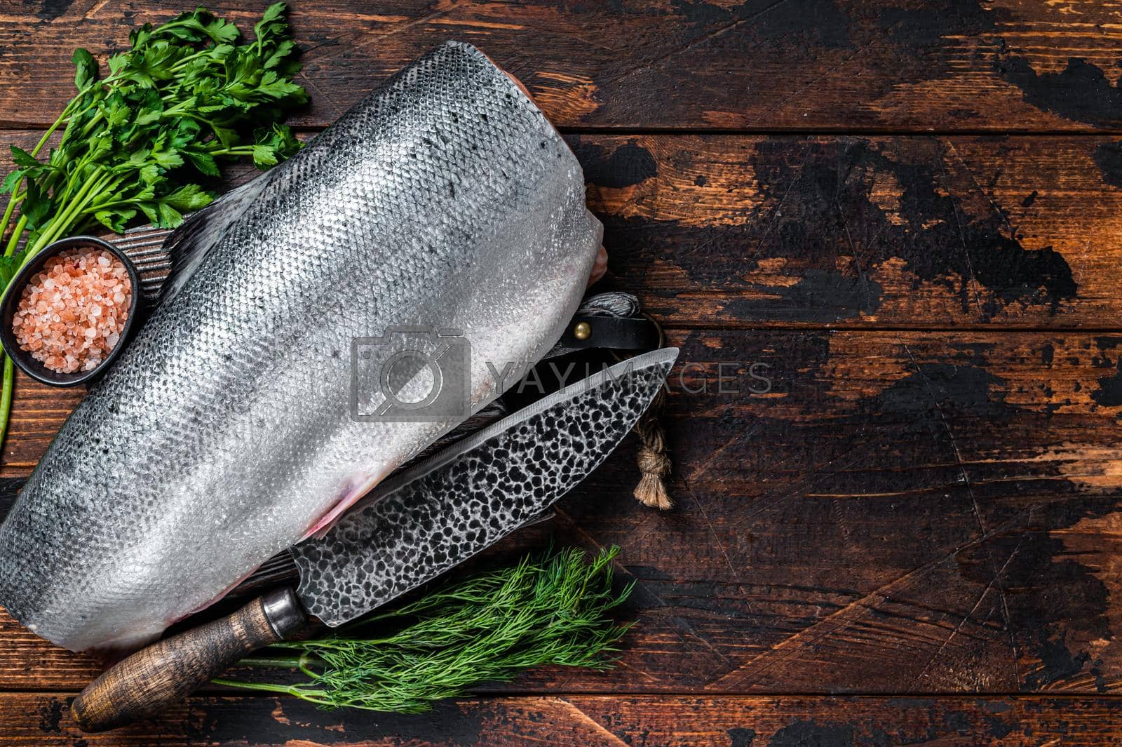 Royalty free image of Big piece of Raw cut salmon fish on a wooden cutting board with chef knife. Dark Wooden background. Top view. Copy space by Composter
