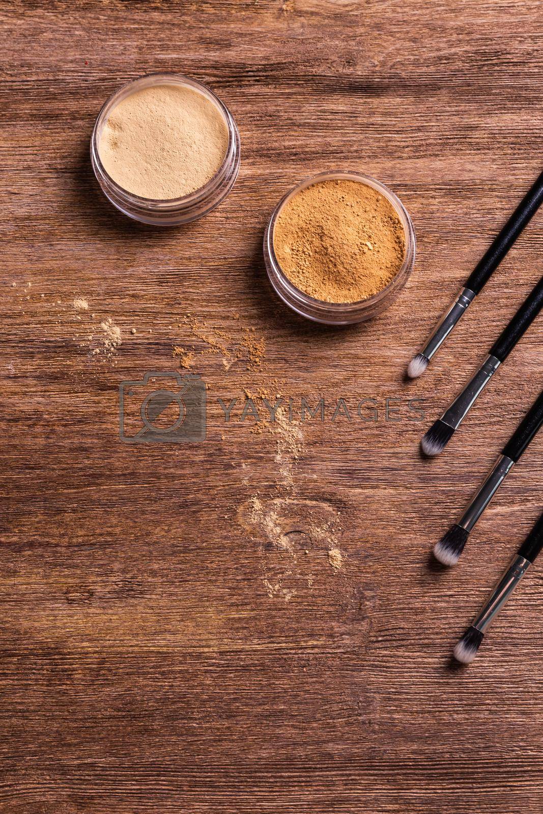 Royalty free image of Loose compact mineral powder for face and a brushes for powder and visage on wooden background. Eco friendly and organic cosmetics. by Satura86