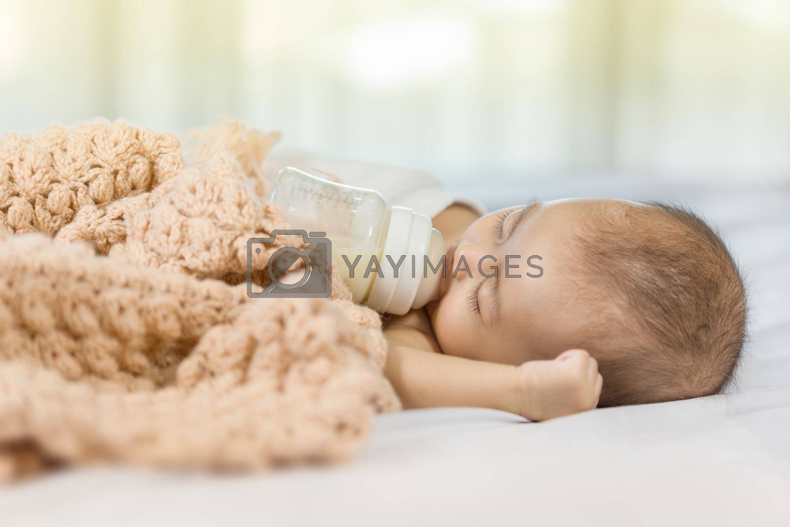 Royalty free image of baby drinking milk from bottle and sleeping on bed by geargodz
