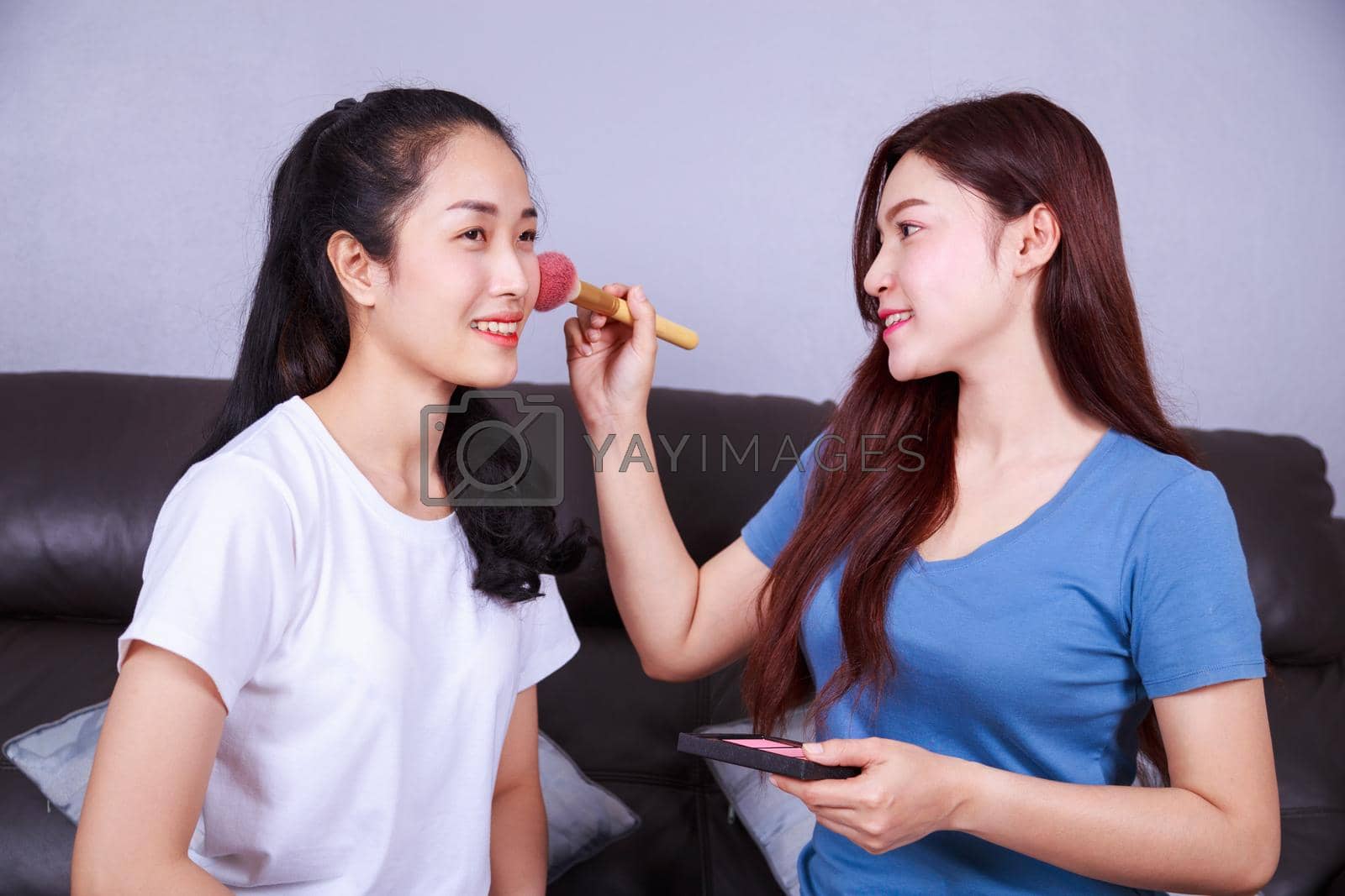 Royalty free image of woman using brush makeup on face her friend by geargodz