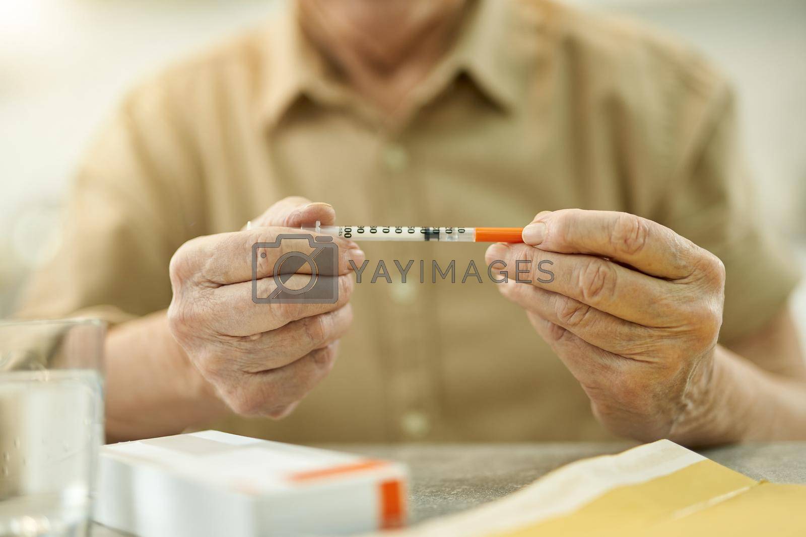 Royalty free image of Senior citizen hoding a thin syringe while at home by friendsstock