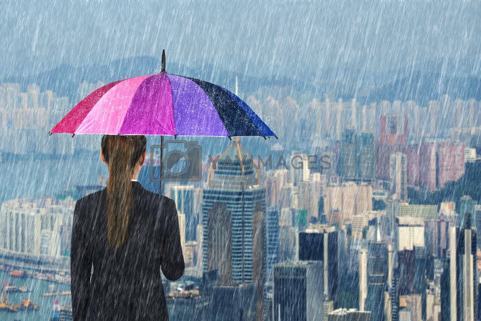 Royalty free image of business woman holding multicolored umbrella with falling rain at city  by geargodz