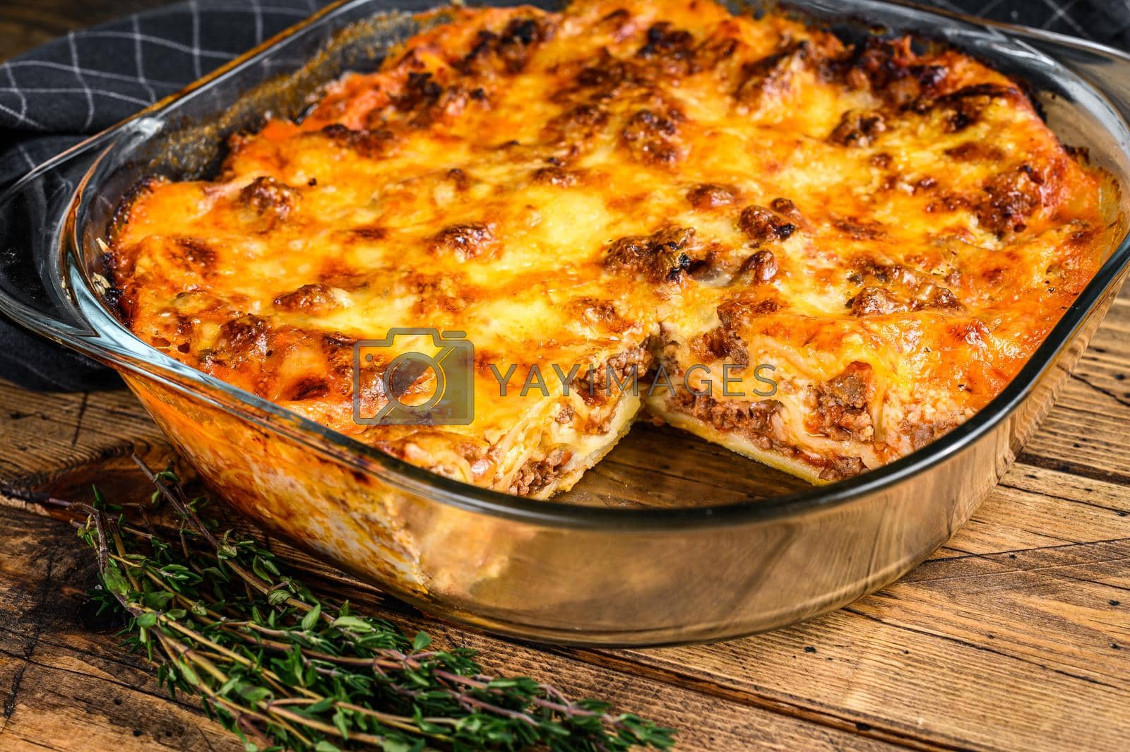 Royalty free image of Lasagna with bolognese sauce and mince beef in a baking dish. Wooden background. Top view by Composter