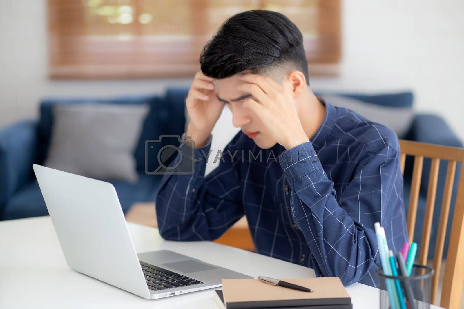 Royalty free image of Young asian business man headache during working on laptop computer with deadline on desk at home, businessman with failure exhausted and tired, stress and worried, frustrated and unsuccessful. by nnudoo