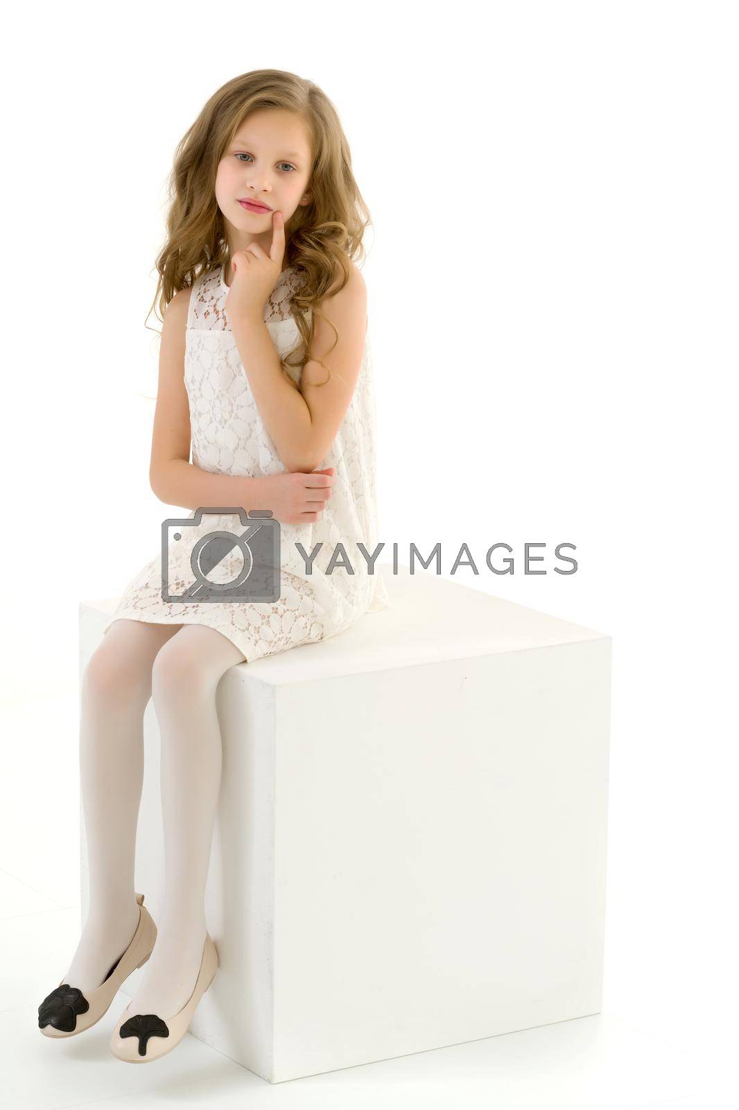 Royalty free image of Girl in Elegant Ivory Dress Sitting on White Cube in Studio by kolesnikov_studio