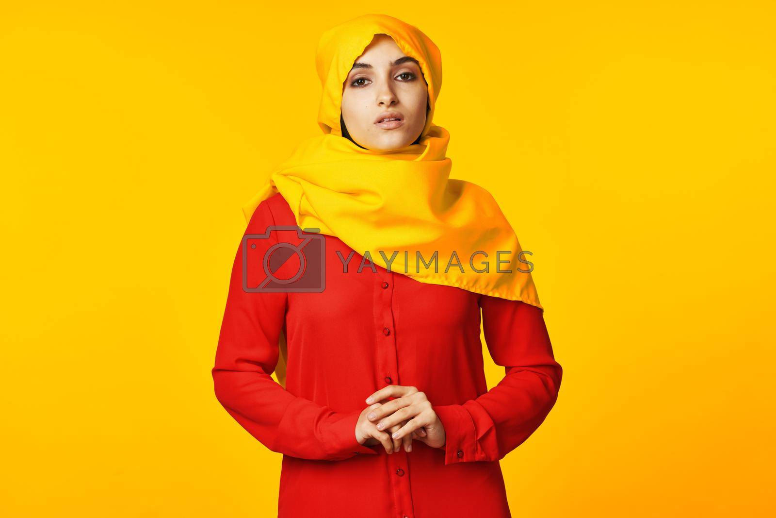 Royalty free image of muslim woman wearing yellow hijab posing ethnicity yellow background by Vichizh